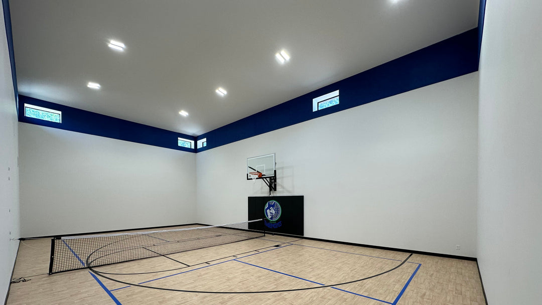 Indoor sports court with basketball hoop and net on a wooden floor.