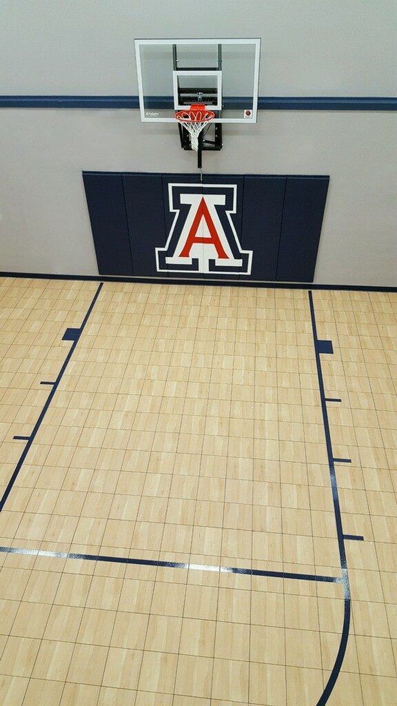 Custom design indoor basketball court by Millz House featuring SnapSports athletic tile flooring with a custom wall bad and wall mount hoop