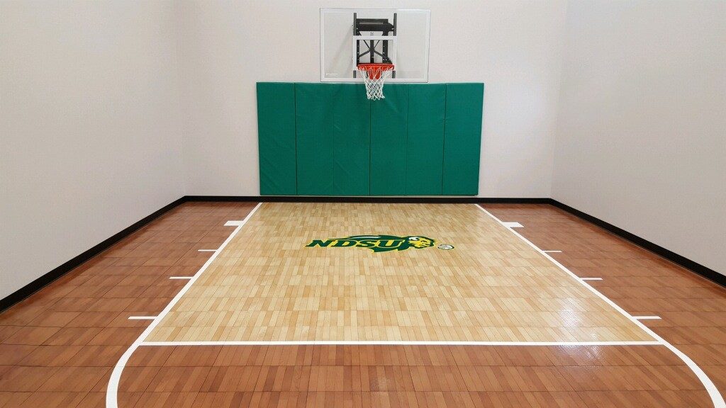 Customized indoor basketball court by Millz House in light and dark maple with custom NDSU logo