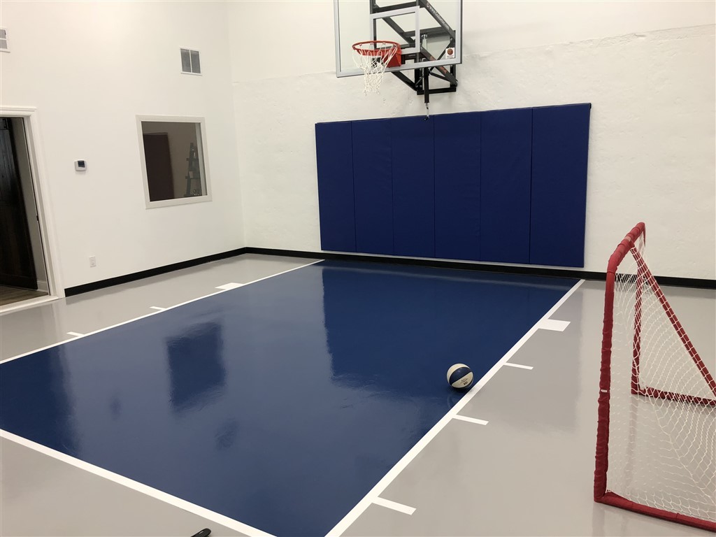 Twin Cities Spring Parade of Homes indoor basketball court featuring an epoxy floor in gray and dark blue installed by Millz House